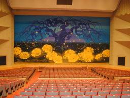 館内ホールの写真。辰野町の特別シンボル「げんじ蛍」、町の木「しだれ栗」、町の花「福寿草」を日展審査員寺石正作先生が描いた原画を伝統の綴錦に織り上げた緞帳です。