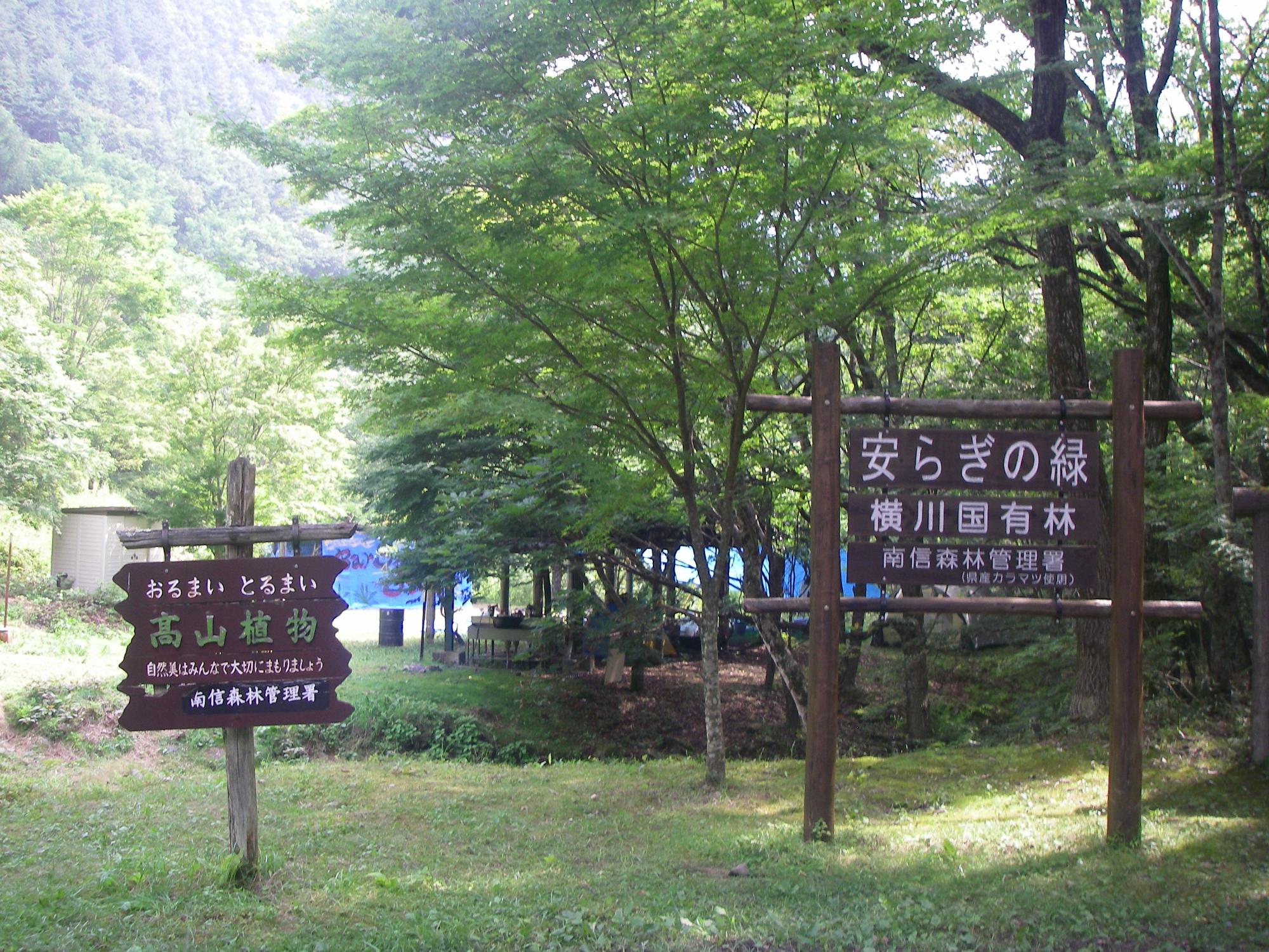 蛇石キャンプ場に建てられた、高山植物と書かれた木造看板と、安らぎの緑と書かれた木造看板の写真