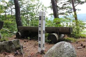 丘の上に立つ国土地理院の三角点の水準点の写真