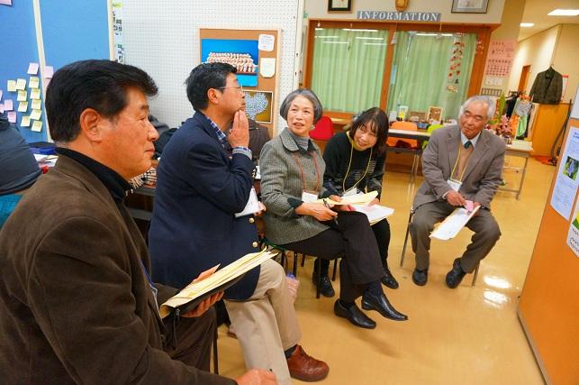 男性と女性が資料を手に持ち、並んで椅子に座っている