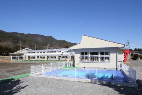 青い空と山に囲まれているプール付きの小野保育園の画像