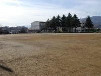 遠くに木々と校舎が写る辰野中学校校庭の写真